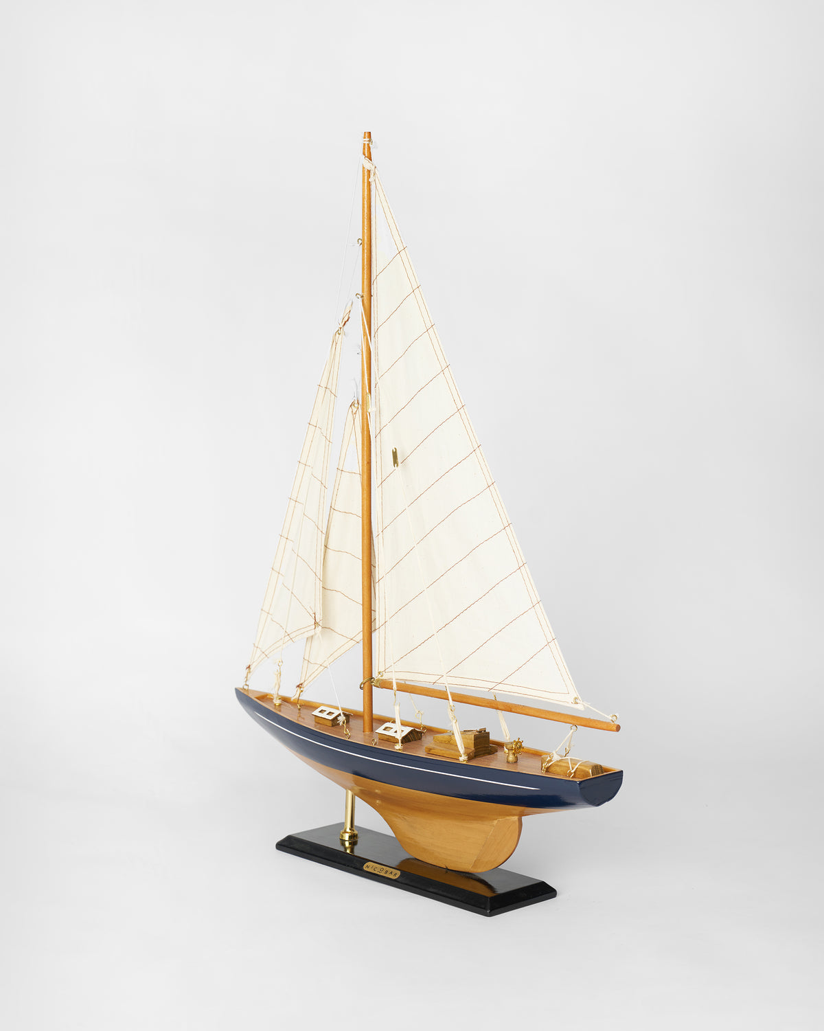 Sail Boat Home Accent with navy hull and cream sails on a black base.