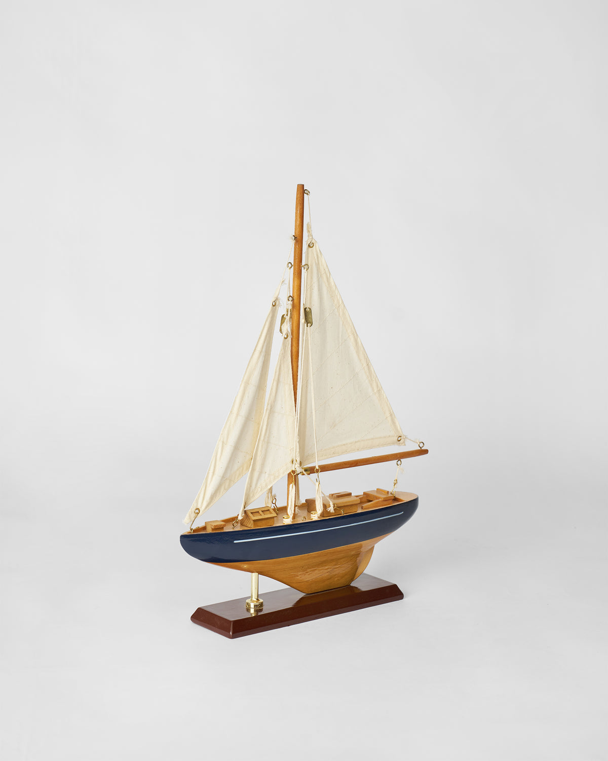 Side view of the Sail Boat Home Accent with navy hull and cream sails.