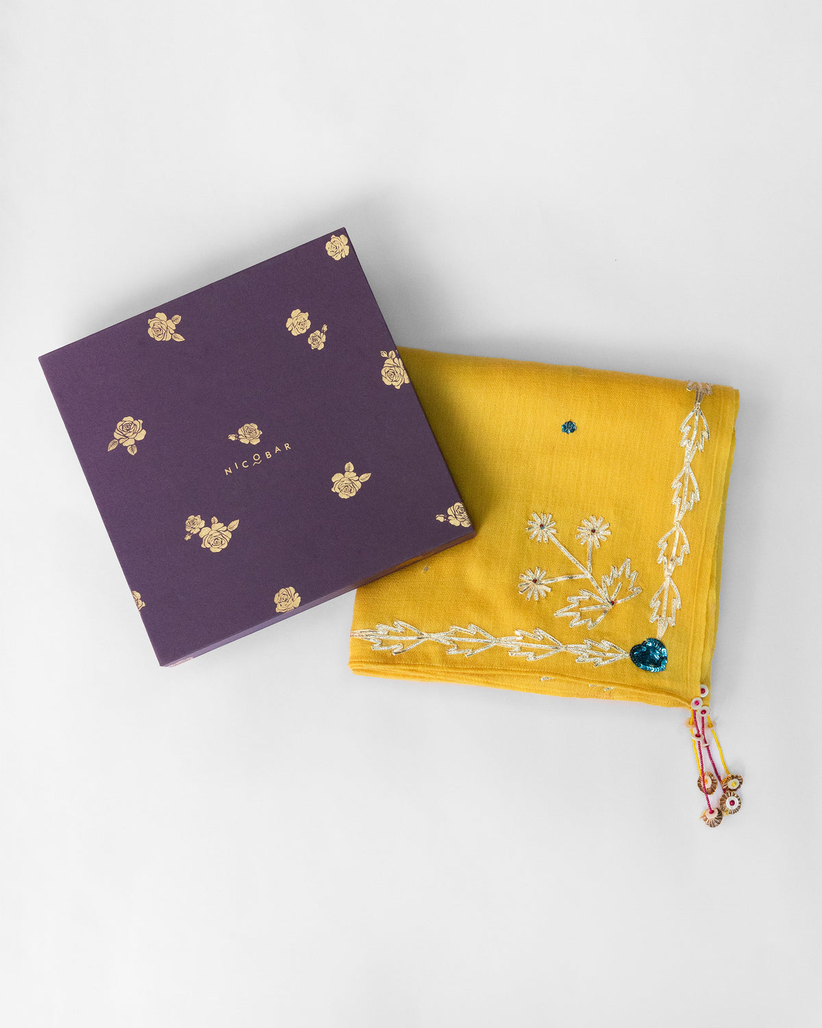 Yellow Saanjh shawl folded beside a purple Nicobar gift box.