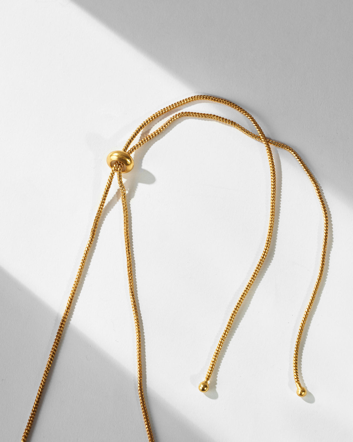 Close-up of the gold adjustable cord and sliding bead on the Gul-Chand necklace.