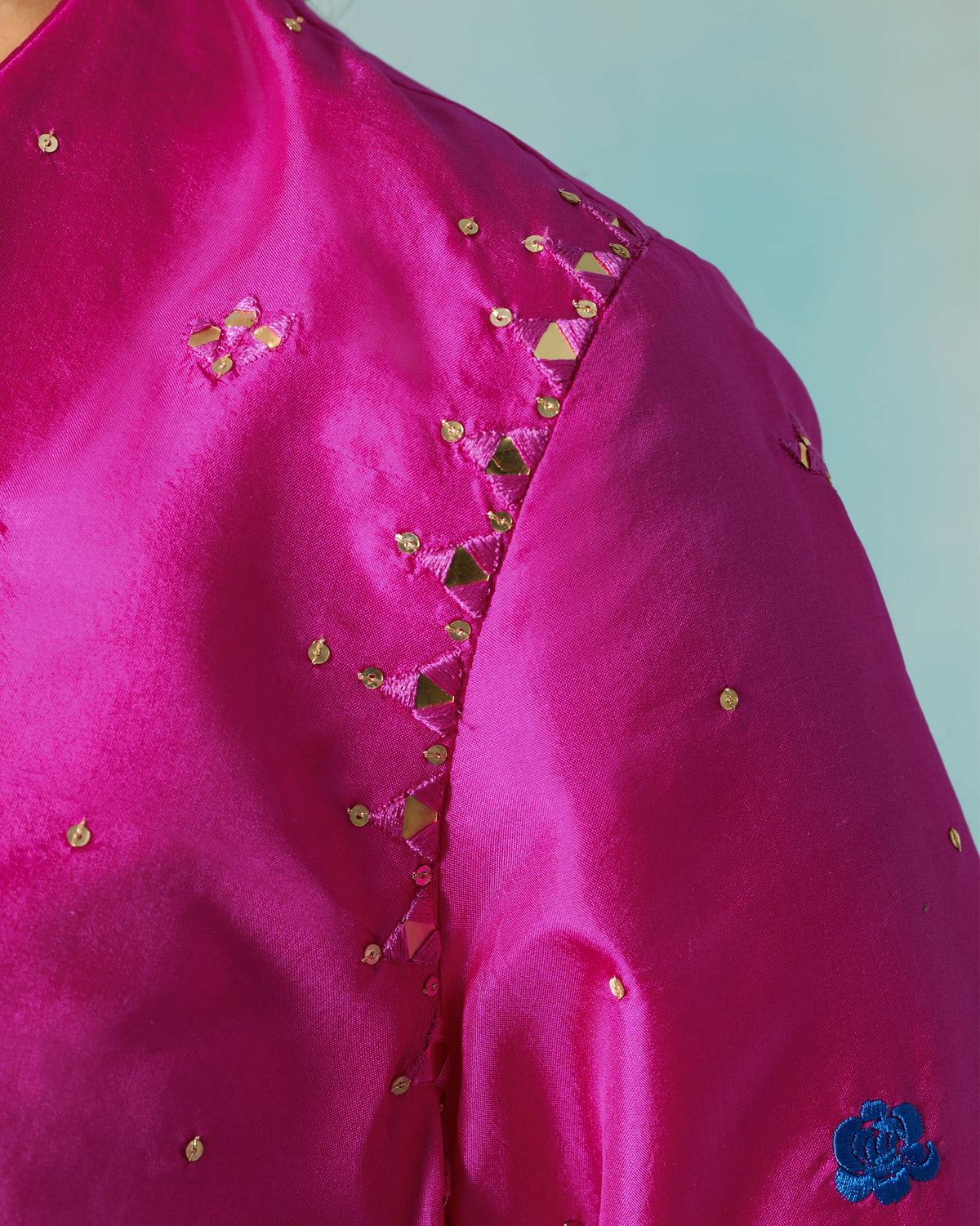 Close-up of mirror and sequin work on the shoulder of a magenta Milni kurta.