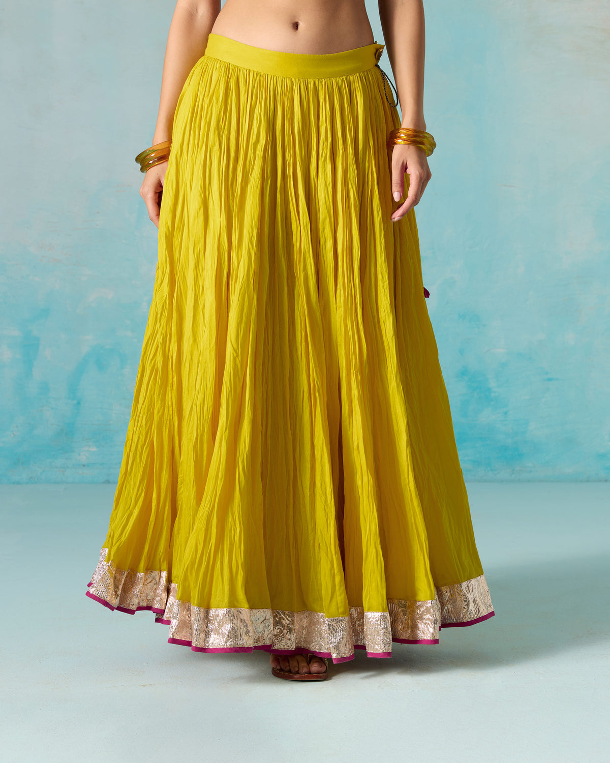 Side view of a yellow Berura skirt with a tasselled tie at the waist.