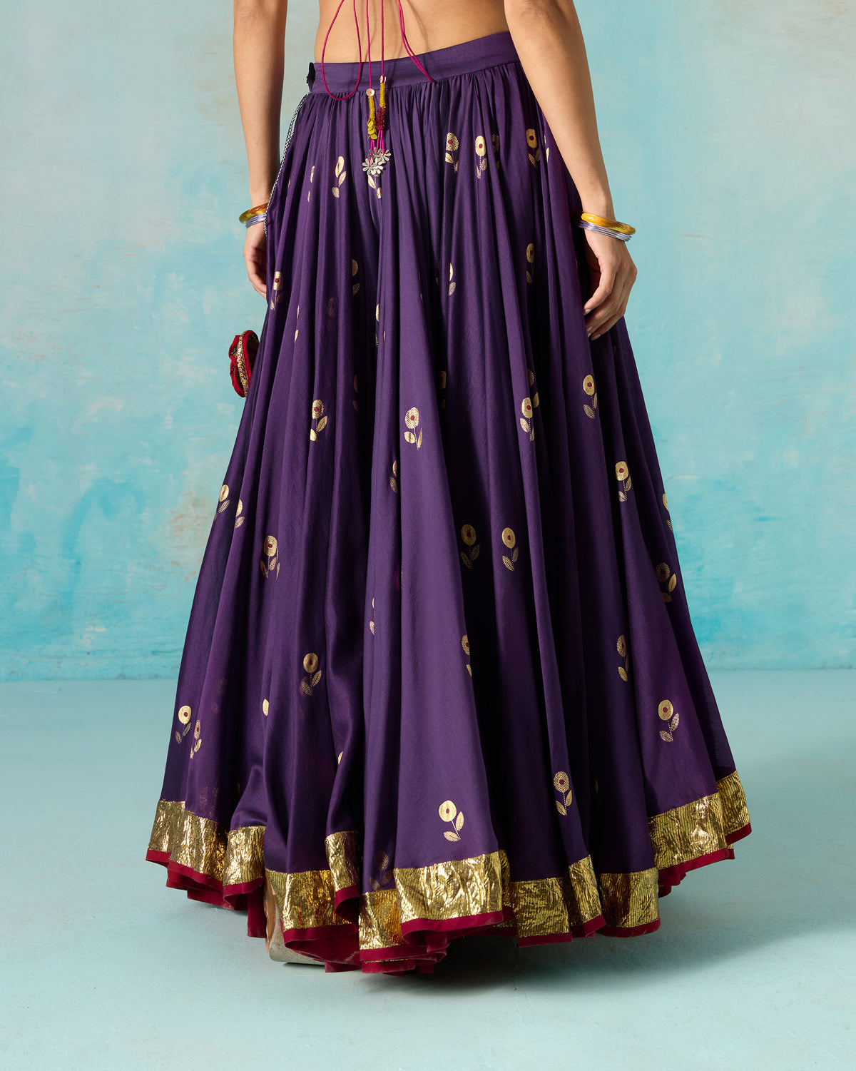 Back of a purple Saaya skirt with gold foil motifs and a gold border hem.