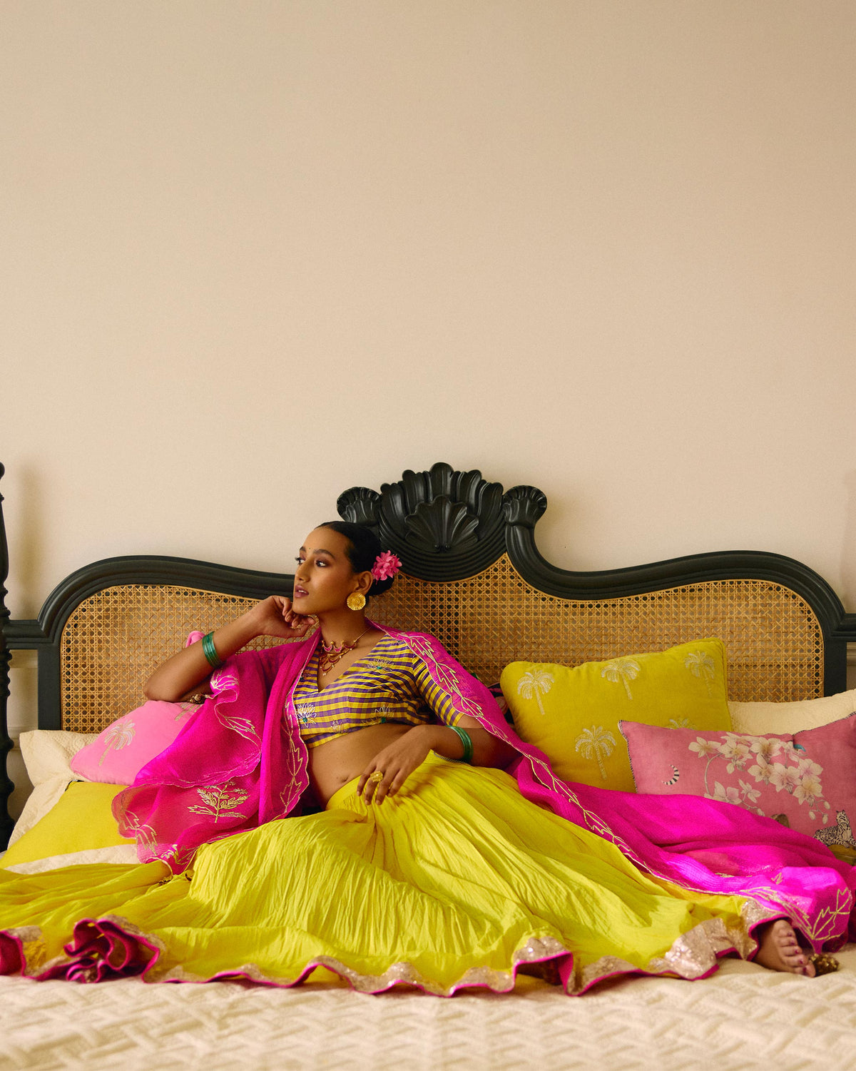 Person wearing a checked Dori blouse, seated on a bed.