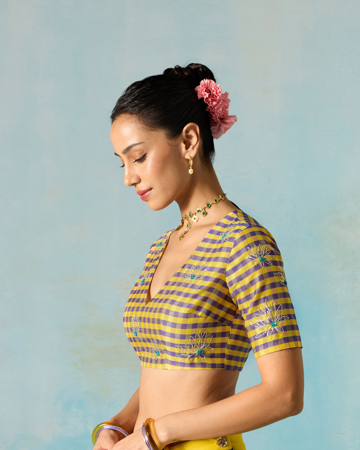 Side view of a checked Dori blouse with embroidered sleeves worn by a person.