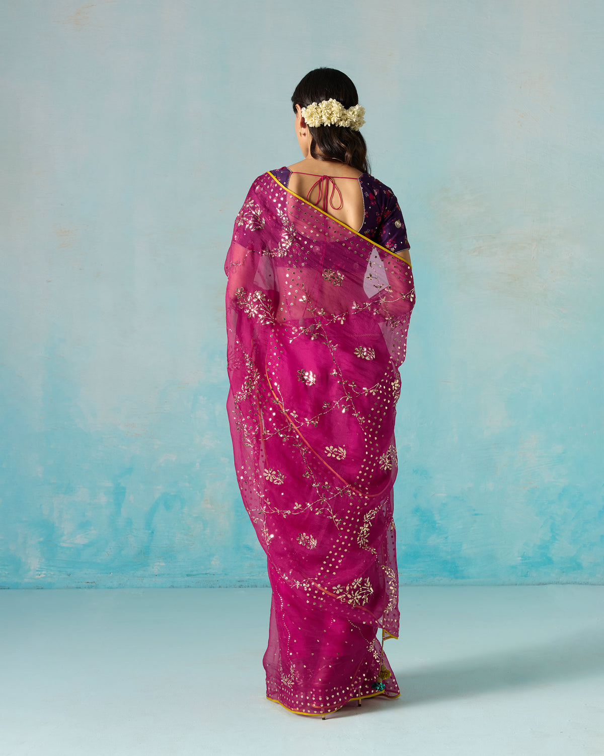Back of a magenta Milan sari with sequin and gold embroidery, worn by a person.