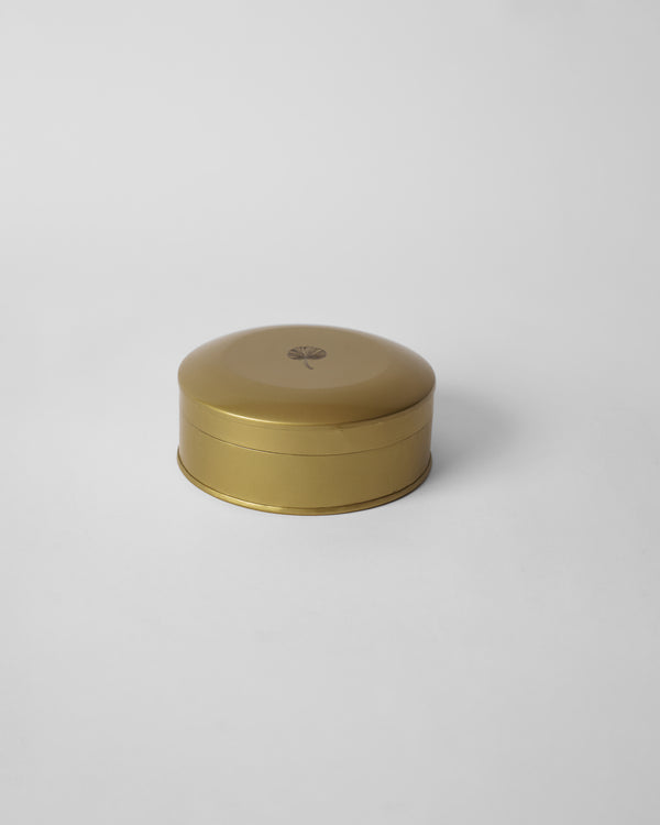 The closed gold tin with a palm logo