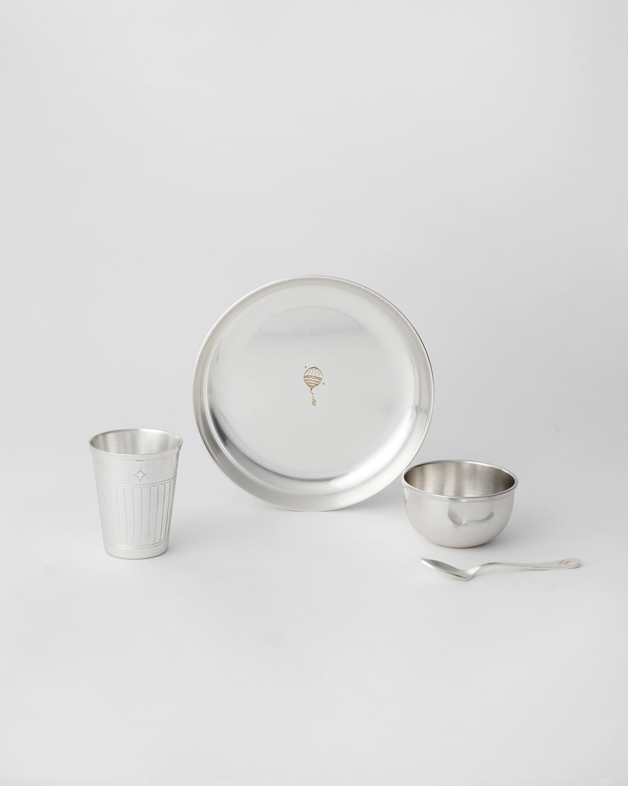 A silver plate, tumbler, katori and spoon laid out