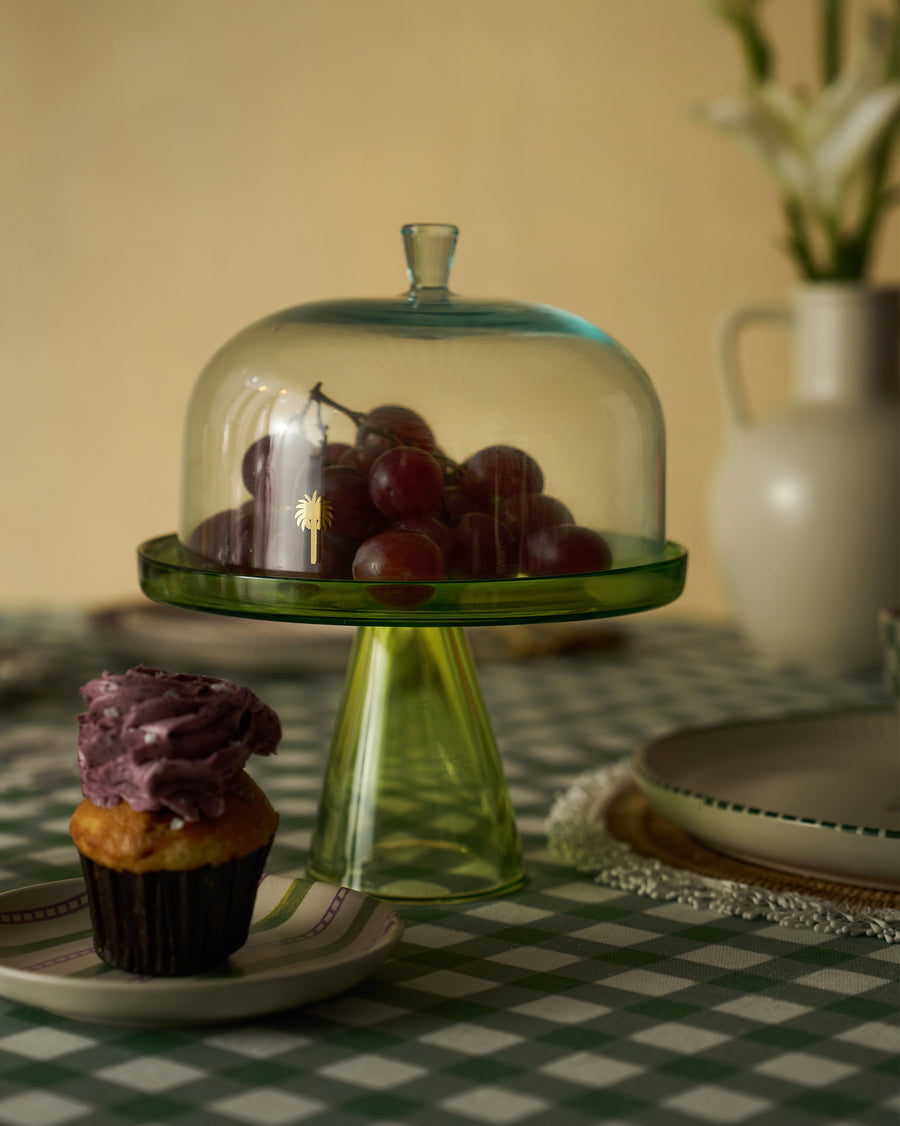 The cake stand with grapes under the dome beside a cupcake