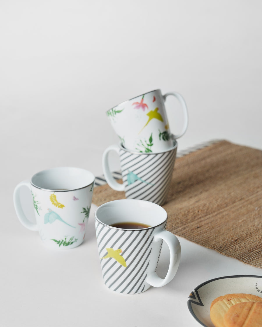 Botanical mugs with coffee on a jute mat beside a plate of biscuits