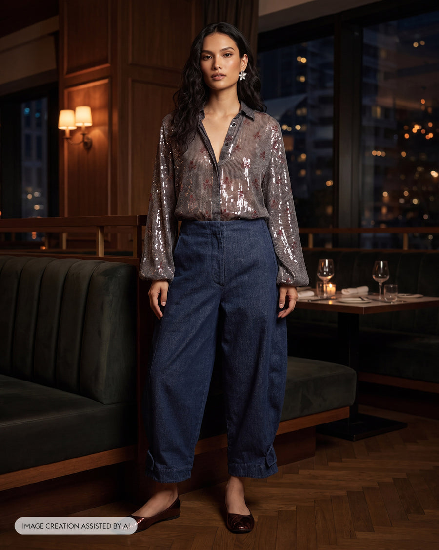 The Bacchus Shirt buttoned and tucked into dark denim in a lamplit restaurant.