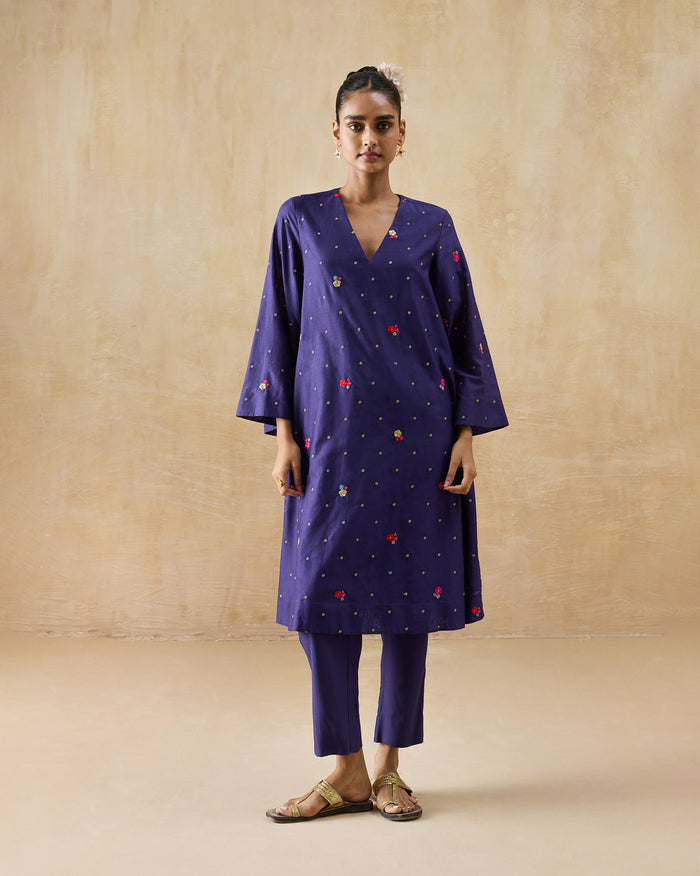 Person wearing a purple Nebula Kurta Set with gold butis and pink florals.