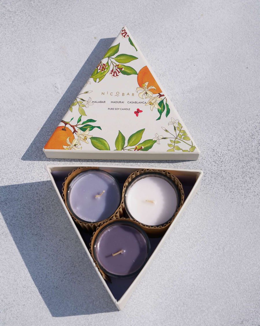 The open triangular gift box with three votives inside.