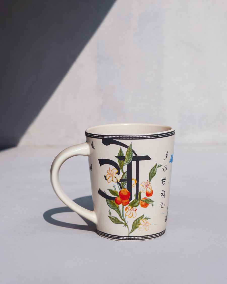The Owl Mug side-on, with the letter ओ.