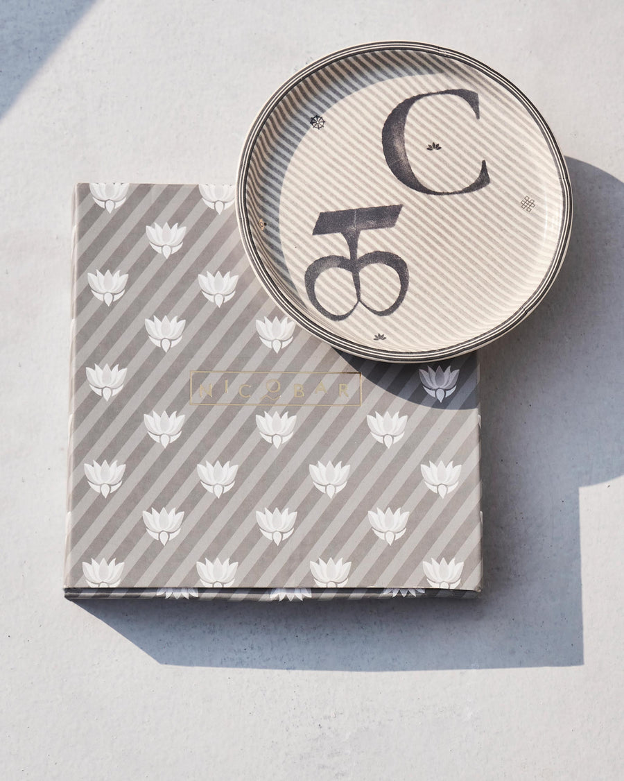 The Akshar Coaster beside its striped gift box.