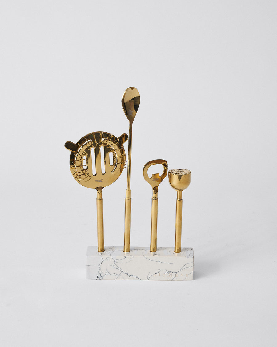 Four gold bar tools standing upright in a white marble base