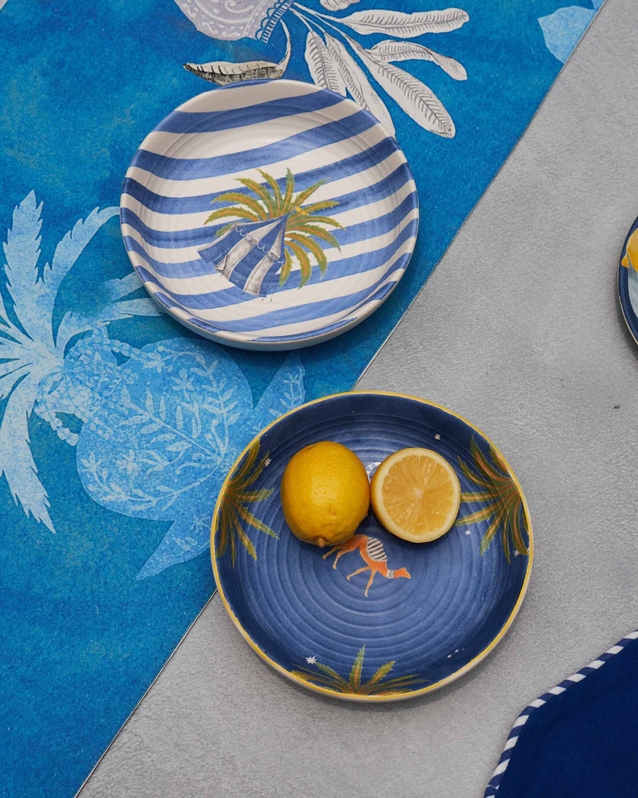Sahara bowls on a blue palm-print cloth, one holding lemon halves