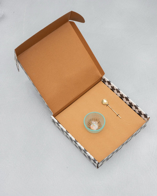 The open box with the glass bowl and gold spoon inside