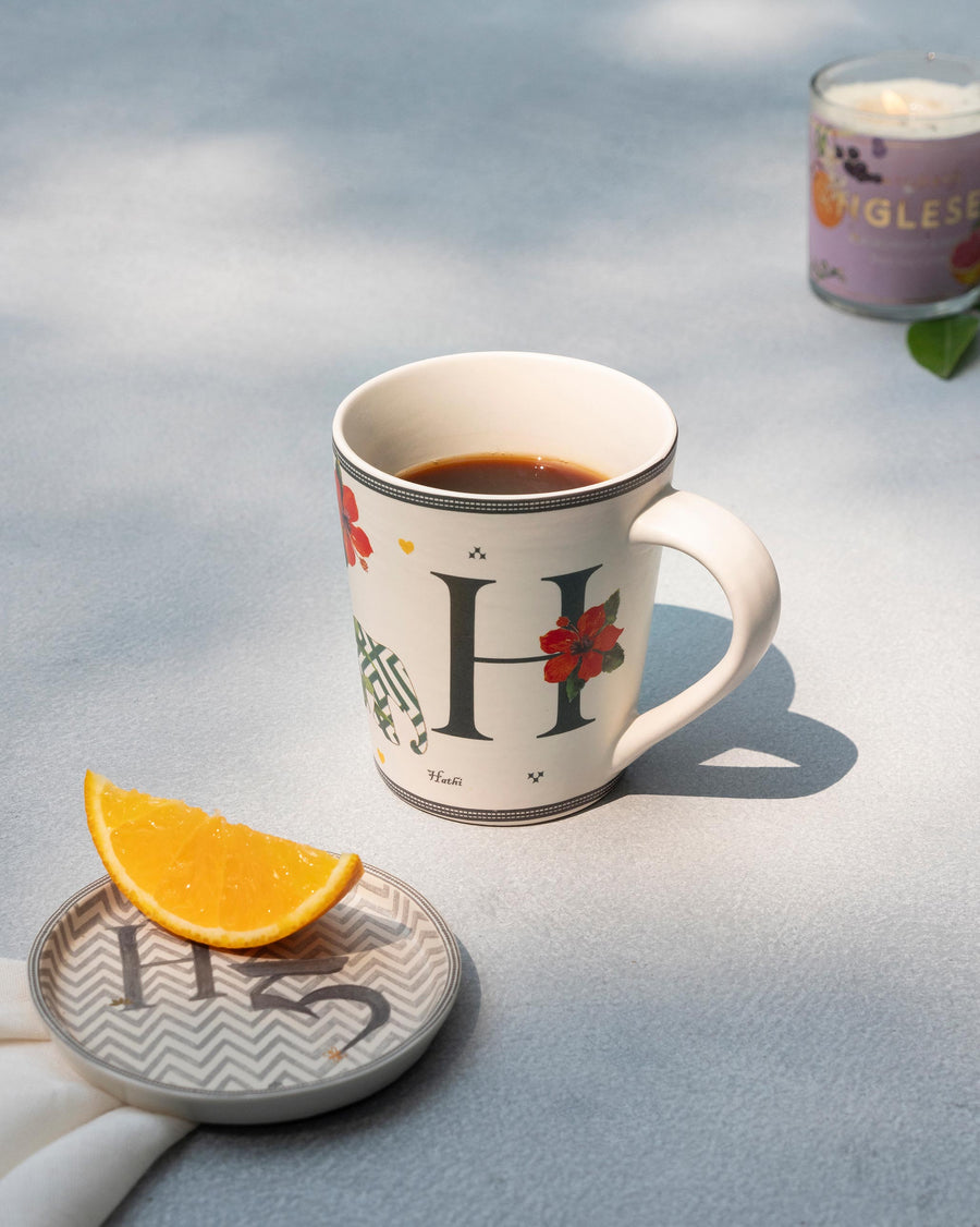 The H mug of coffee beside its matching H coaster