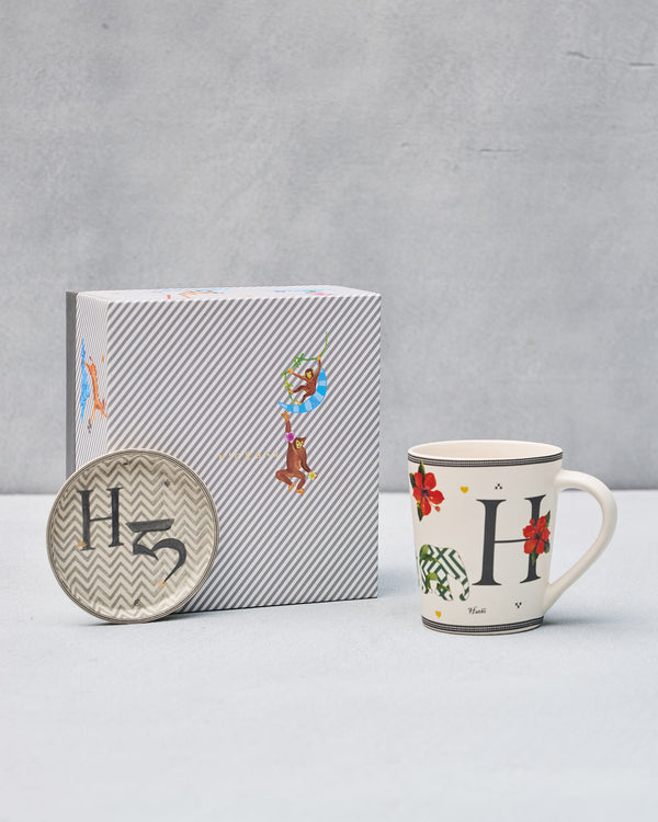 The H mug and coaster beside the striped gift box
