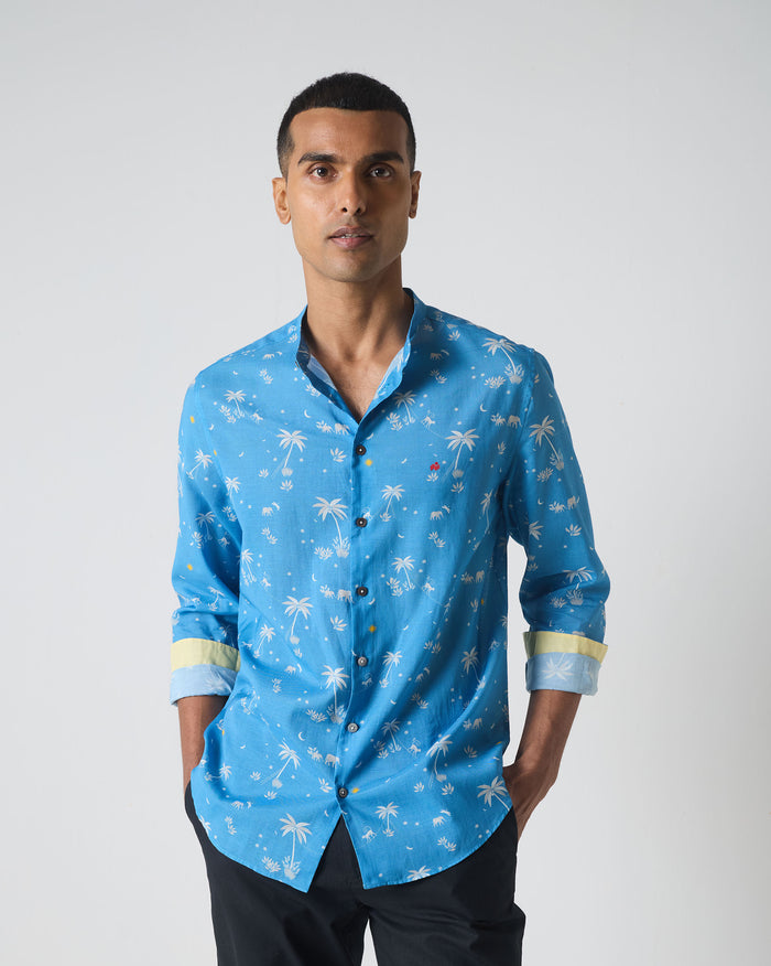 Person wearing a blue Nawab shirt with white palm and elephant print.