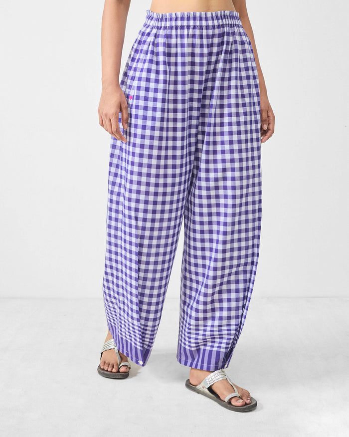 Person wearing purple and white checked Wide Paper Bag Trousers with an elastic waist.