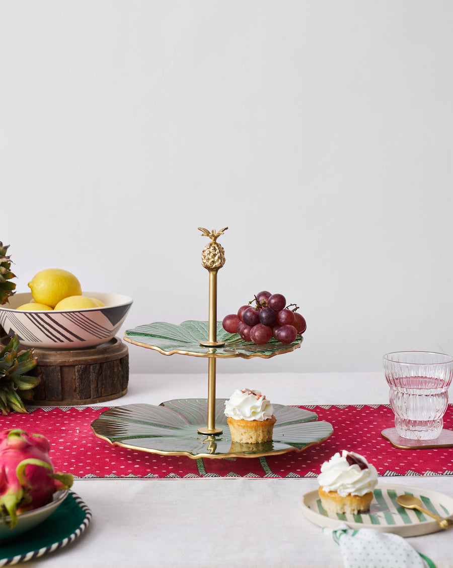 The Phool cake stand with cupcakes and fruit on a red runner