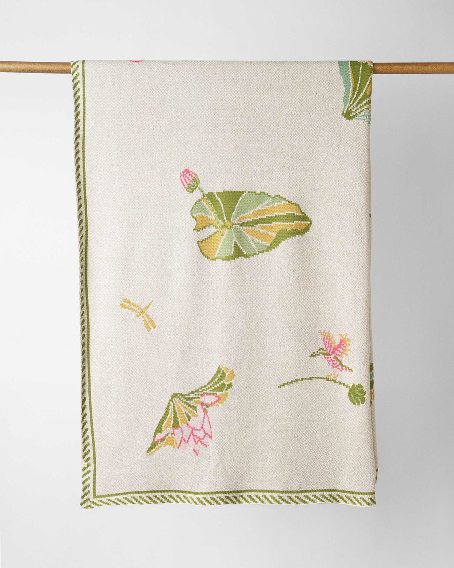 The throw hanging from a rail, lily pads and lotuses on cream