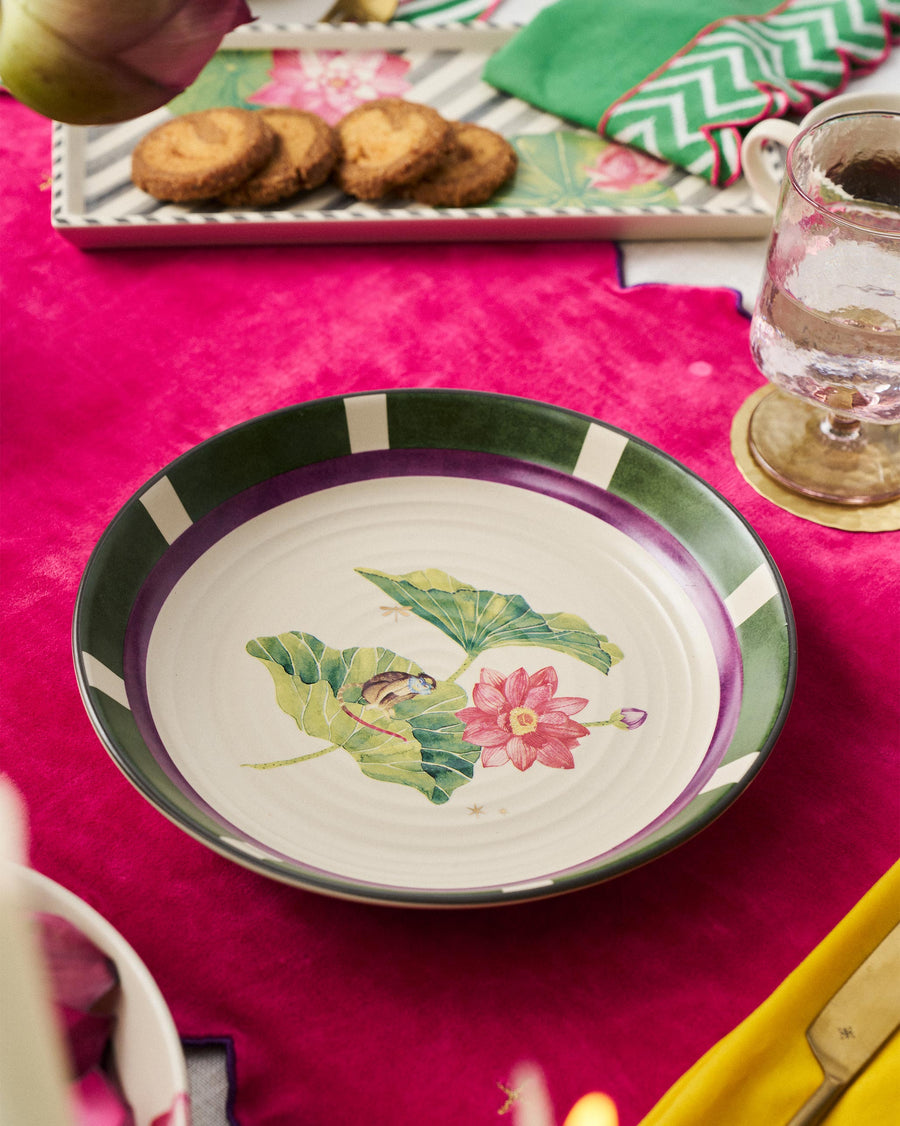 The Lotus Garden plate on a bright pink cloth beside cookies