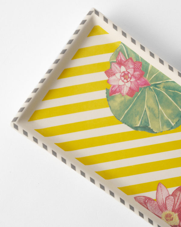 Close view of a pink lotus and lily pad on yellow stripes