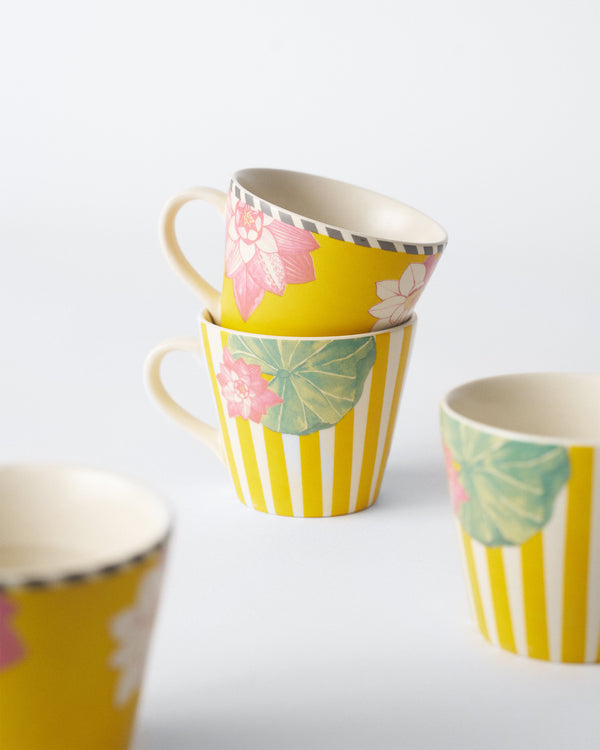 Mugs stacked, the solid yellow with lotus clusters