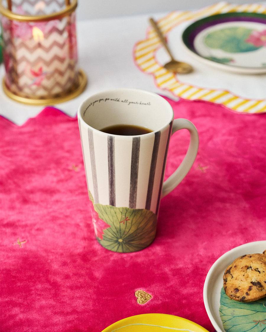 The Float tall mug of coffee on a pink cloth beside cookies