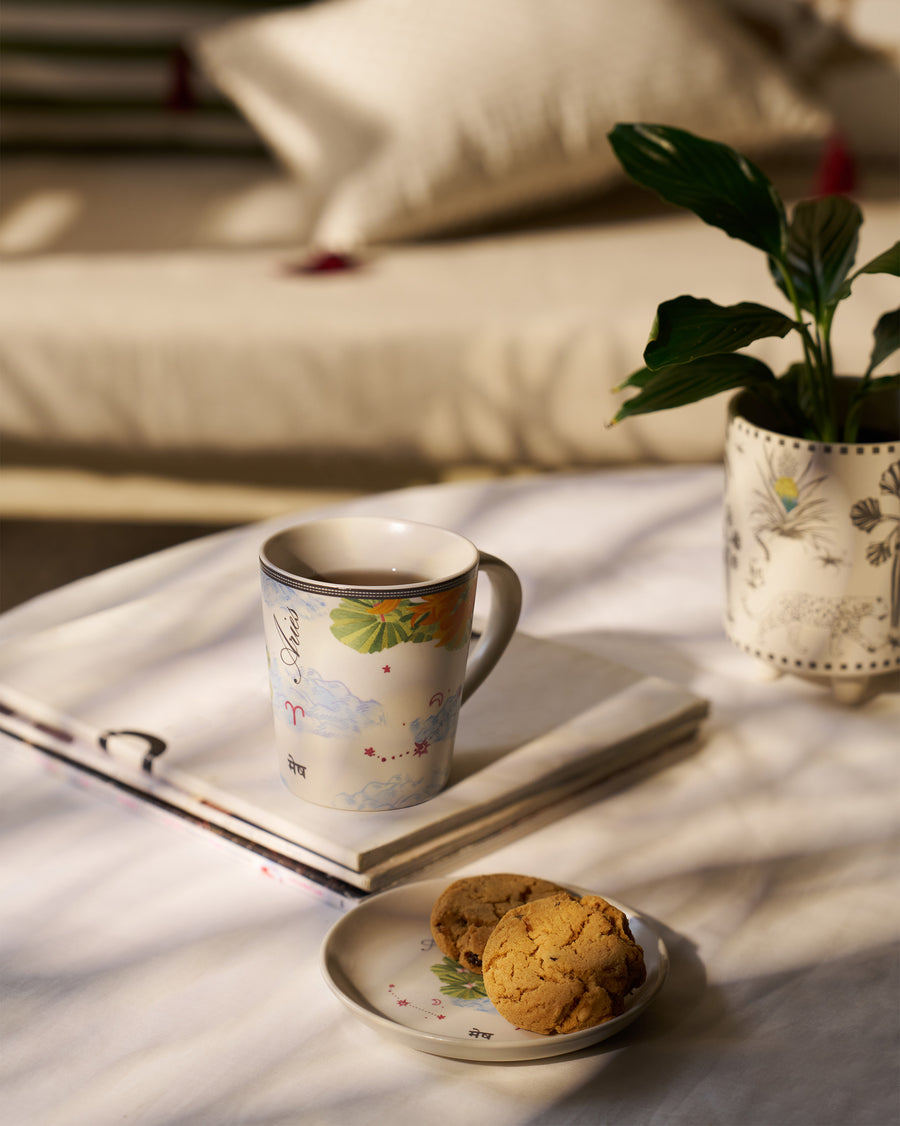 The Aries mug on a book beside a plate of cookies