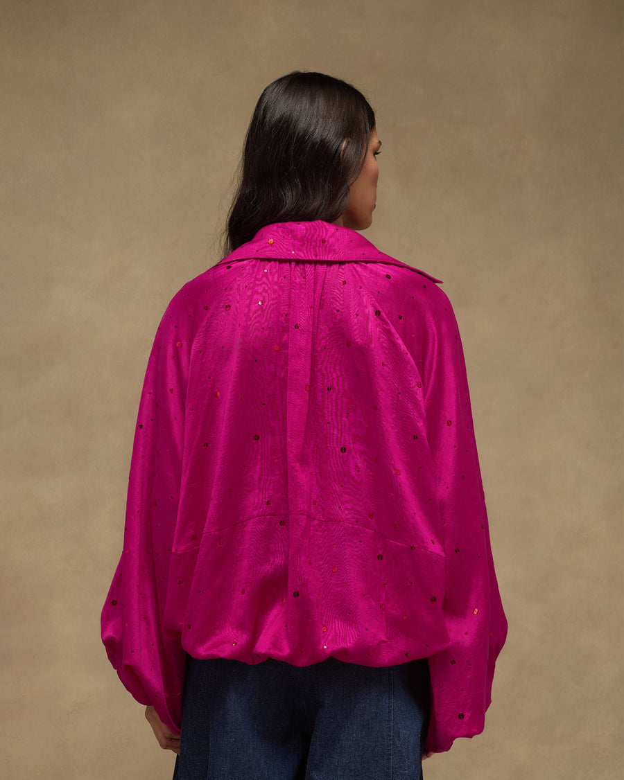 Back view of the fuchsia Cloud Overlay, gathered at the hem, with sequins scattered across the cloth.
