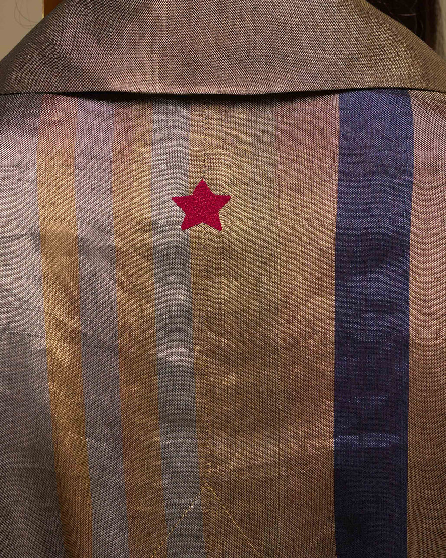 Close-up of the small red star embroidered at the centre back of the Sera Trench, just below the collar.