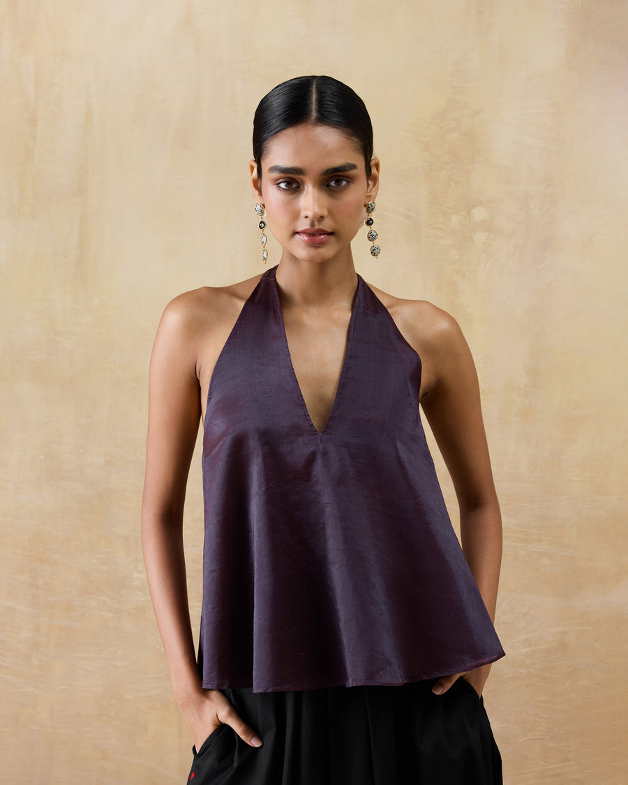 The Sashay Top, a plum metallic tissue halter top with a deep V-neckline, worn with black trousers.