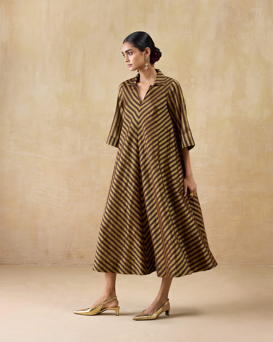 The Areva Dress seen at an angle, its flare swinging, with gold heels.