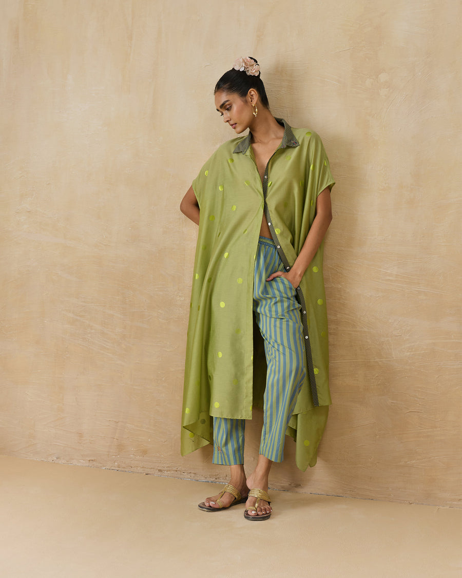 The Strut Kaftan, a green polka foil print Cotton Silk kaftan, worn open over striped co-ord pants.