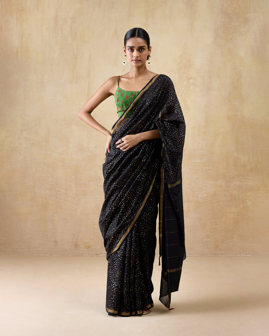 The Riverbank Sari, a black cotton silk sari with gold foil and gold stripes at the border, worn with a green blouse.