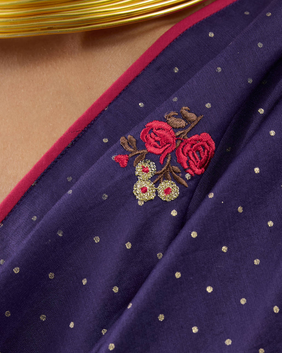 Close-up of the Midnight Dance Sari: embroidered red roses on foil-dotted purple, with a pink binding at the edge.