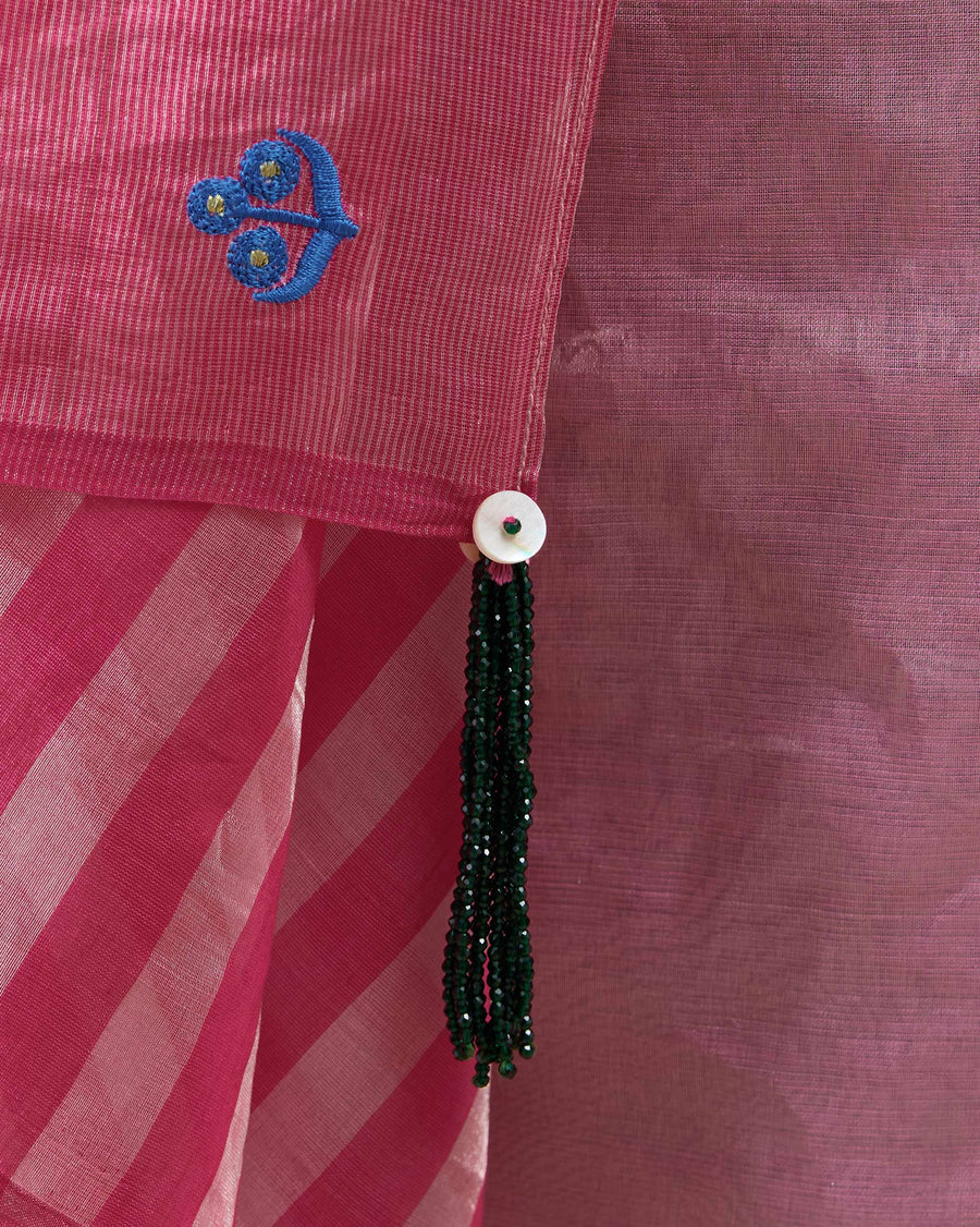 Close-up of the pallu corner of the Blush Sari: a blue embroidered icon and a green bead tassel.