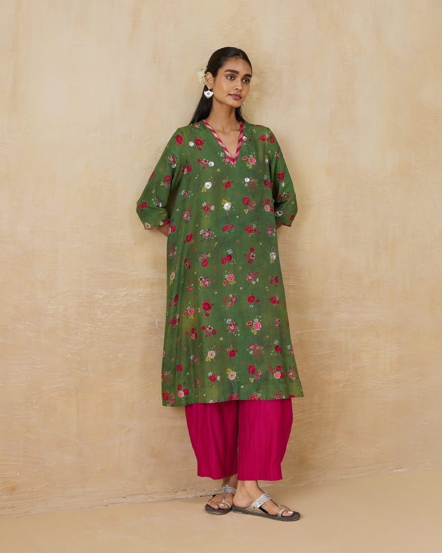 The Cascade Kurta, a long olive green cotton silk kurta with a floral print and a V-neck, worn over pink Serene Pants.