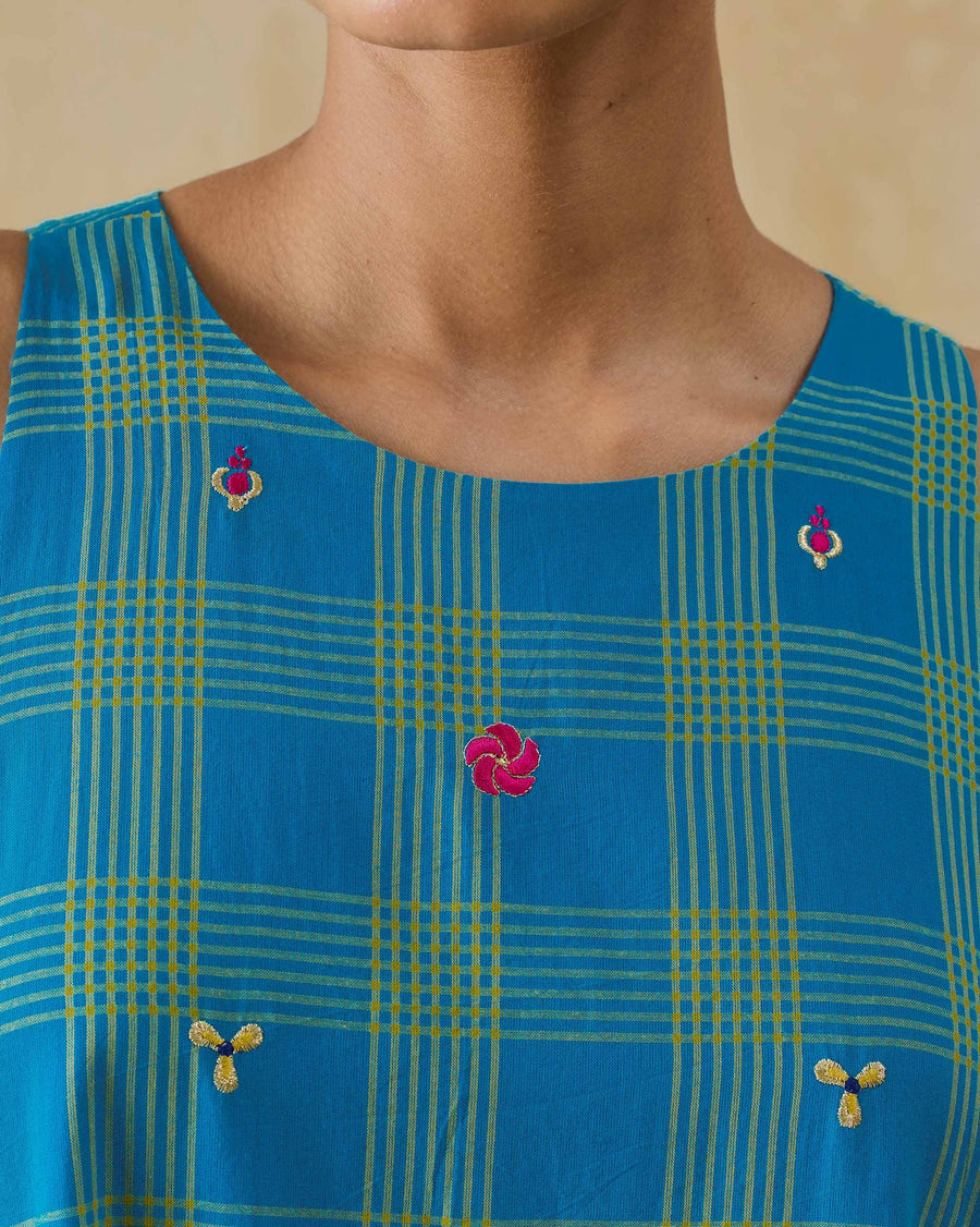 Close-up of the neckline of the Nimbus Dress, with small pink and gold embroidered flowers on the check.