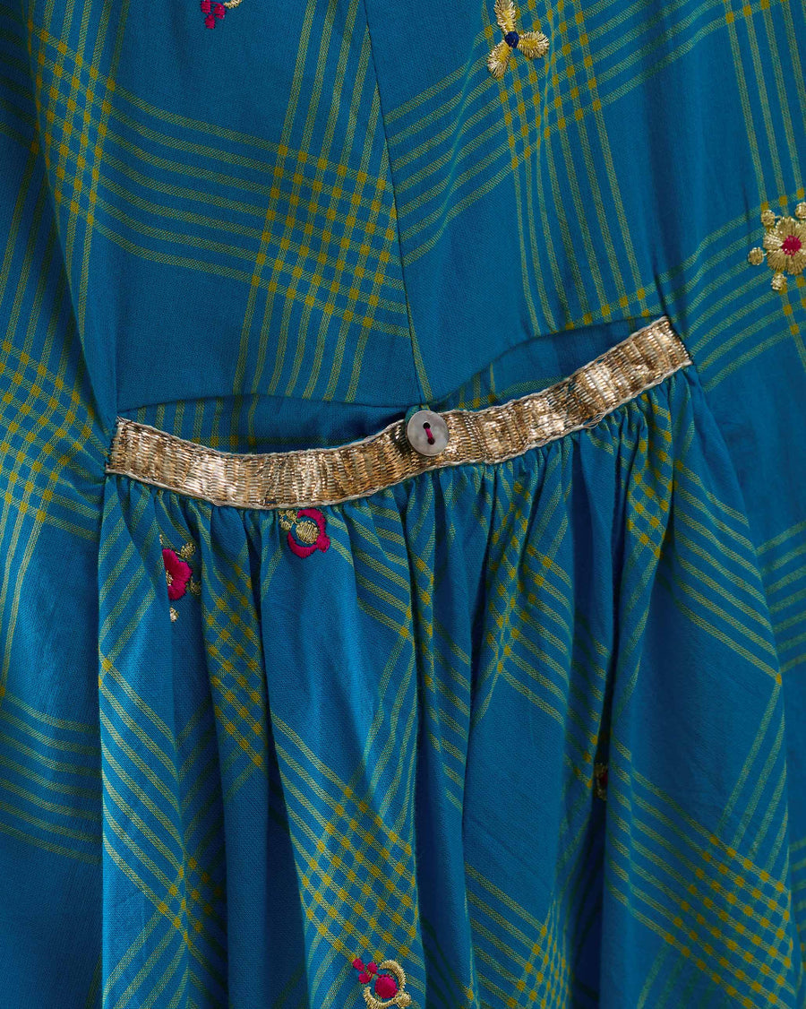 Close-up of the pocket of the Nimbus Dress, edged in silver gota above gathered checks.