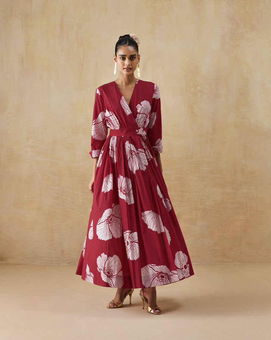 The Nico Dress, a long red wrap dress in organic cotton voile with a large white poppy print and full sleeves.