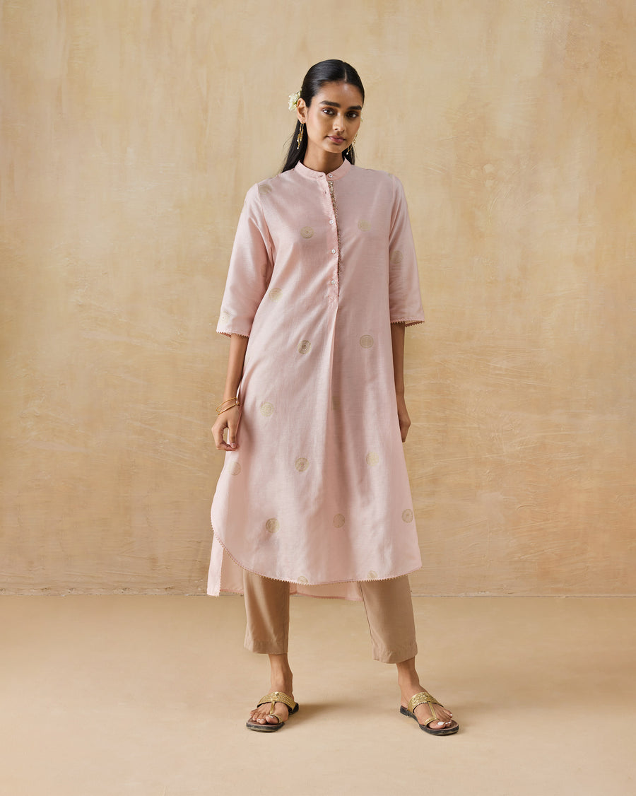 The Radiant Kurta, a long soft pink cotton silk kurta with a mandarin collar and gold foil dots, worn over beige trousers.