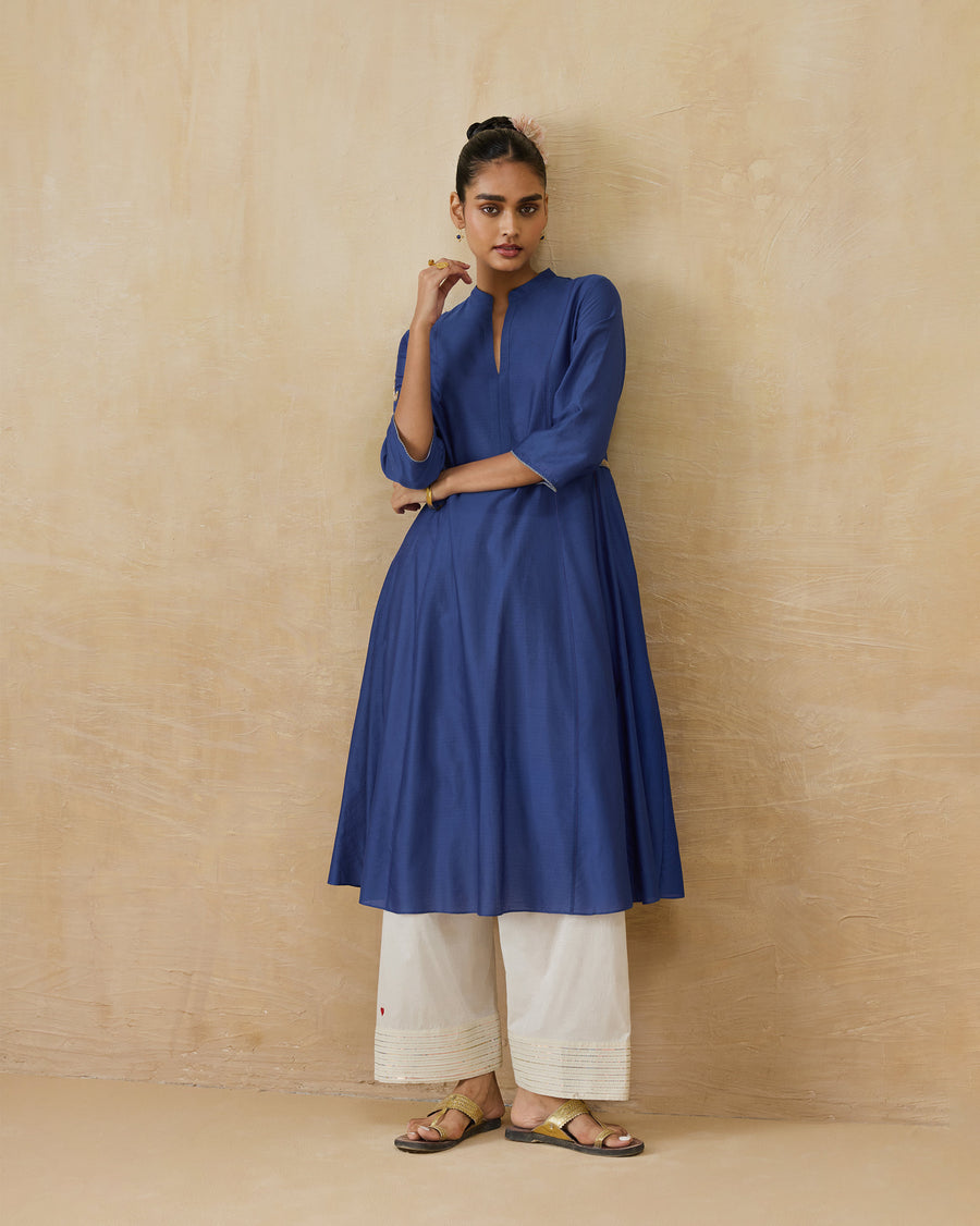 The Moonsong Kurta, a long cobalt blue cotton silk A-line kurta with a mandarin collar, worn over ivory trousers.