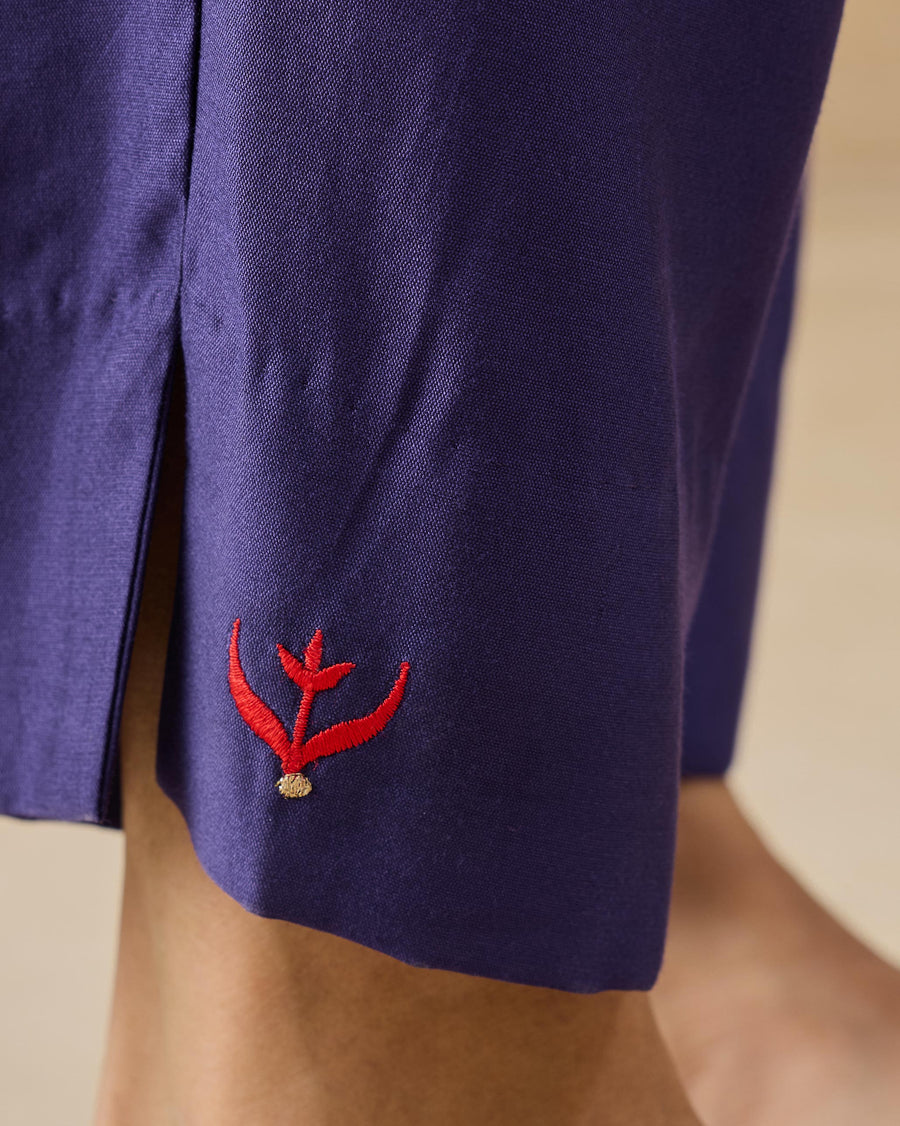 Close-up of the hem of the Darjeeling Pants, with a red and gold tulip embroidered above a small side slit.