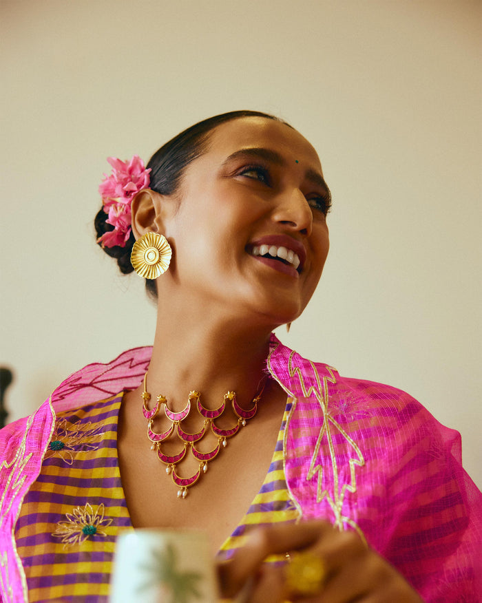 Close-up of a person wearing a gold Gul-Chand necklace with pink crescent stones.