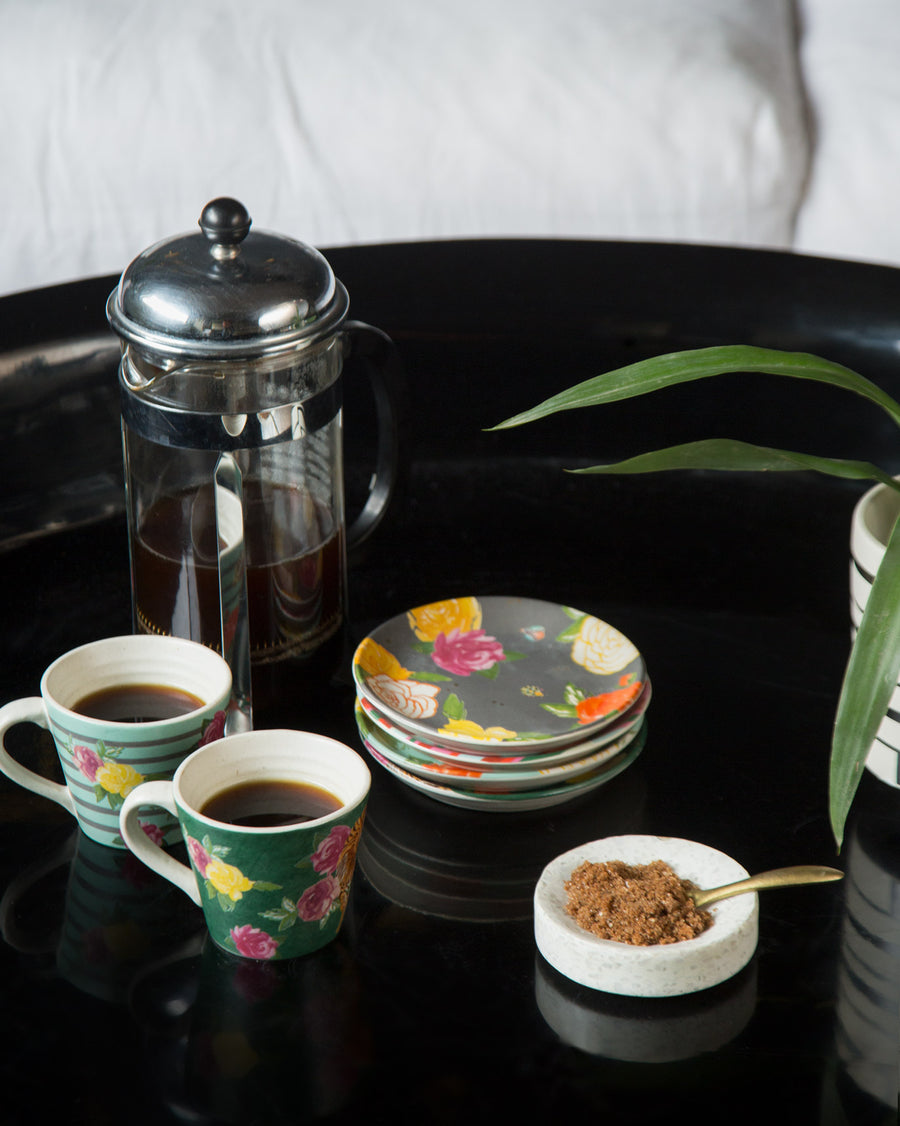 Serai mugs of coffee beside a French press on a black tray